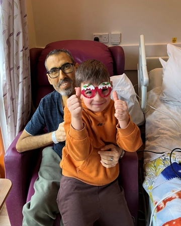 Young boy sits on his dad's lap at the Hospice