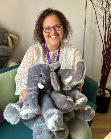 Diana smiles and sits with toy elephants